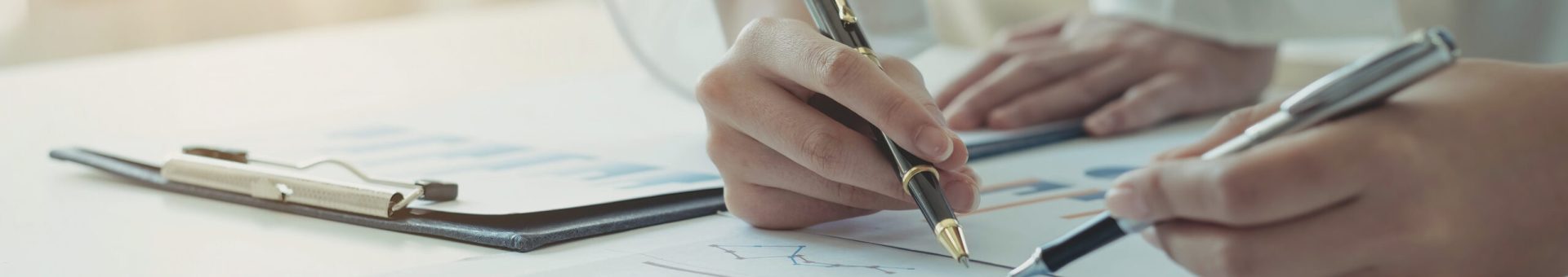 Close-up of two women's hands pointing to a turnover chart while talking on a wooden table in the office. group support concept