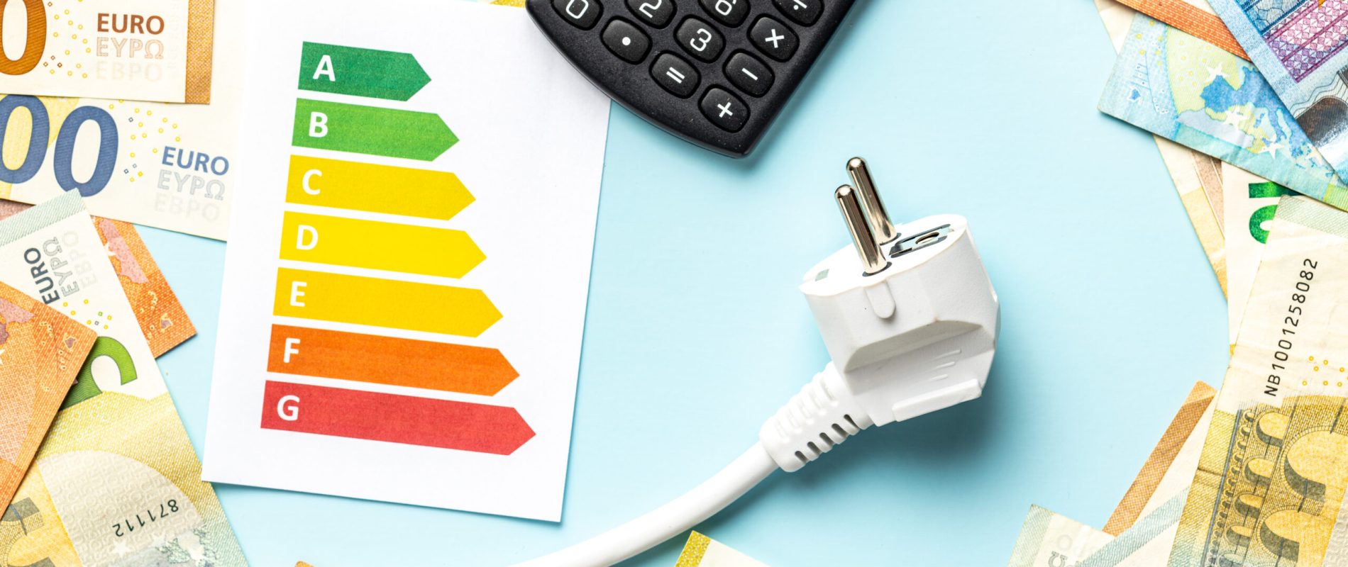 Electric plug, calculator, energy label and euro money on the blue background. Concept of increasing electric prices. Top view.