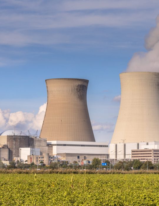 Nuclear power plant with steaming cooling towers under blue summer sky in Belgium