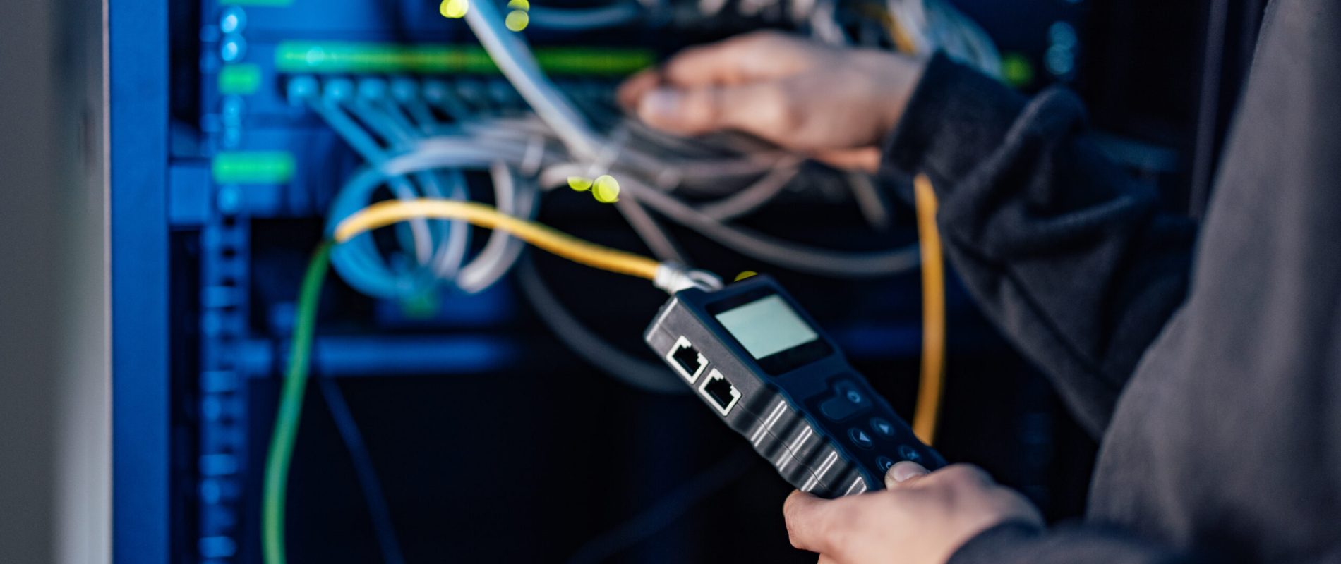 Close-up image of technician working with network cable tester.