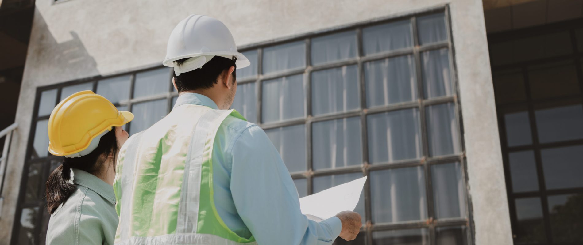 Smart civil architect engineer inspecting and working outdoors structure building site with blueprints, engineering and architecture concept, maintenance engineer team working in front of building.