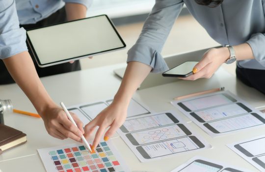 Cropped shot of young UX designer team working on smartphone application project with using digital tablet in modern office room.