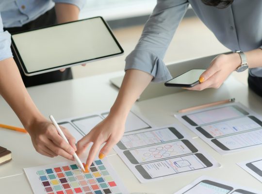 Cropped shot of young UX designer team working on smartphone application project with using digital tablet in modern office room.